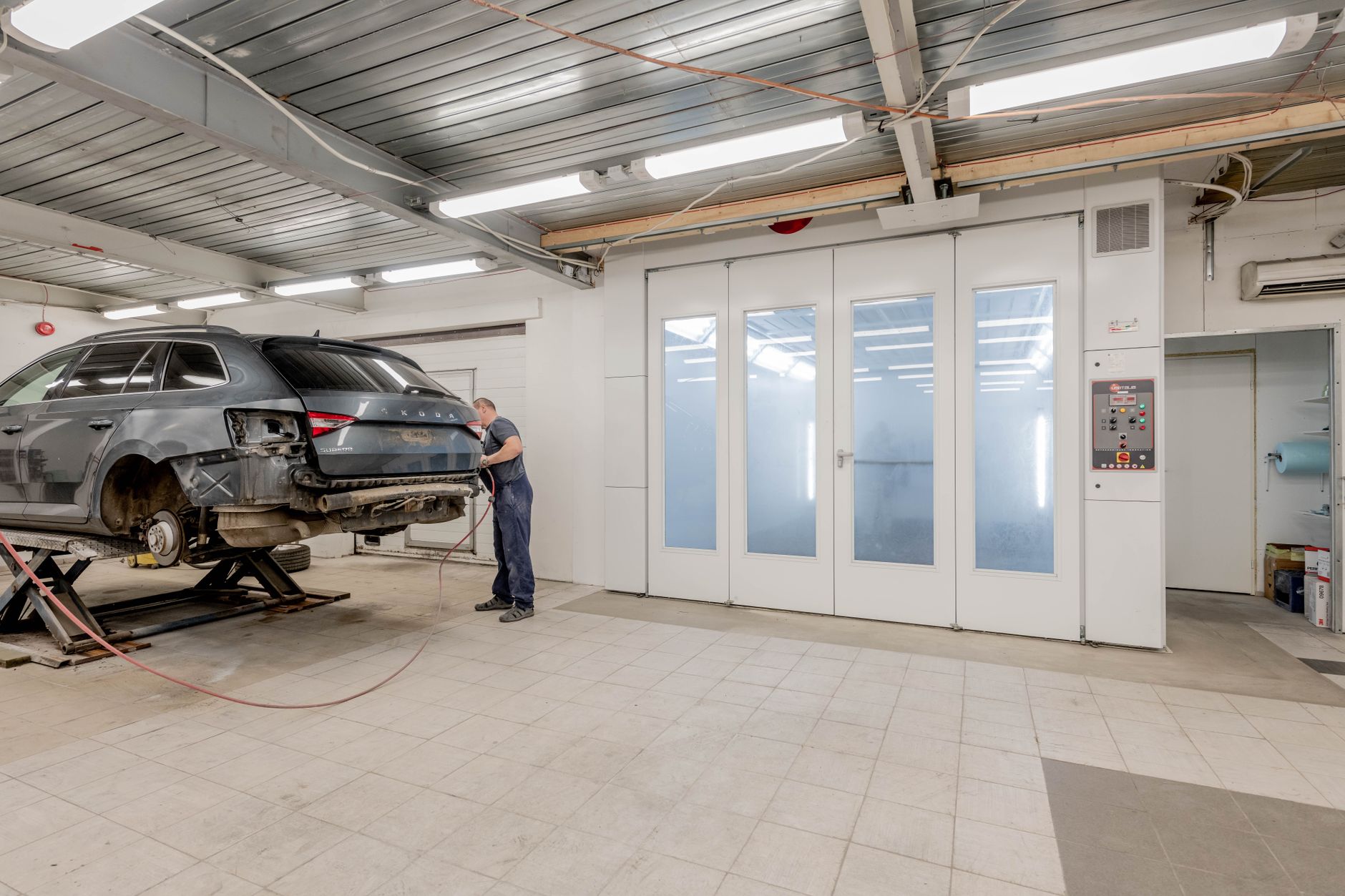 Technician working on a vehicle inside an auto body workshop